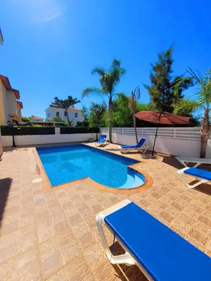 a swimming pool with two chairs and an umbrella at Ayia Napa Marina Luxury Villas - Pearl in Ayia Napa
