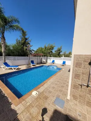 a swimming pool with blue chairs next to a building at Ayia Napa Marina Luxury Villas - Pearl in Ayia Napa