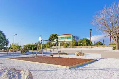 a playground with a swing set in a parking lot at Villa Rosaleen - Ayia Napa Resort Center in Ayia Napa