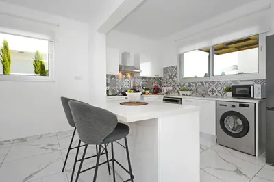 a white kitchen with a counter and chairs in it at Villa Evelin - Ayia Napa Resort Center in Ayia Napa
