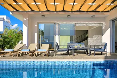 a patio with chairs and a swimming pool at Villa Evelin - Ayia Napa Resort Center in Ayia Napa