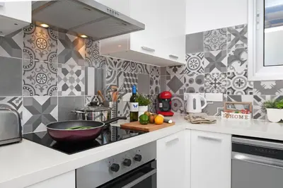 a kitchen with white cabinets and black and white tiles at Villa Evelin - Ayia Napa Resort Center in Ayia Napa