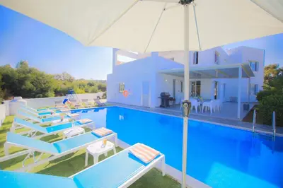 a swimming pool with lounge chairs and an umbrella at Akefalou Bay Villa in Protaras