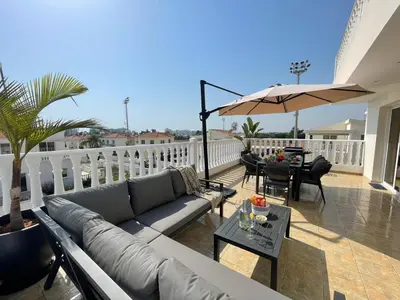 a living room with a couch and an umbrella on a balcony at Star Apt in front Nissi whit Sea View in Ayia Napa