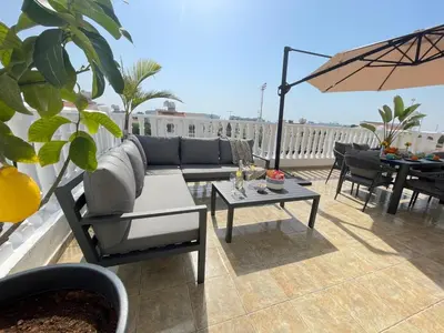 a patio with a couch and tables and an umbrella at Star Apt in front Nissi whit Sea View in Ayia Napa