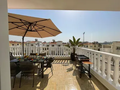 a patio with a table and an umbrella on a balcony at Star Apt in front Nissi whit Sea View in Ayia Napa