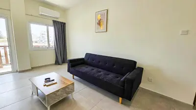 a living room with a black couch and a coffee table at Sky Ward City Rooms, 150m from Chabad Lubavitch in Larnaka