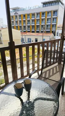 a glass table with two cups on a balcony at Sky Ward City Rooms, 150m from Chabad Lubavitch in Larnaka