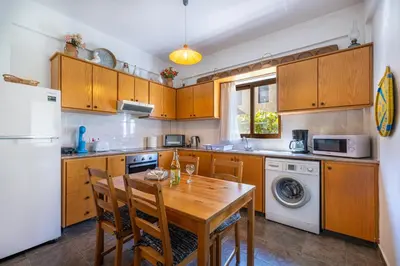 a kitchen with a wooden table and a refrigerator at JP Pool House in Trimiklini
