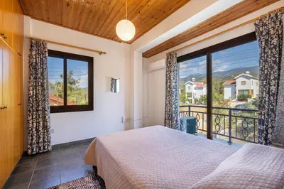 a bedroom with a bed and a large window at JP Pool House in Trimiklini