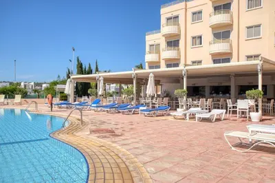 a hotel with a swimming pool and chairs and a building at Kama Lifestyle Modern apt with sea view in Protaras