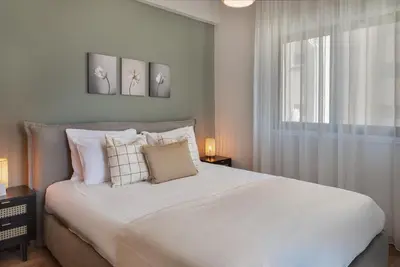 a bedroom with a white bed with two paintings on the wall at Phaedrus Living Larnaca Tsimintia Retreat in Larnaka