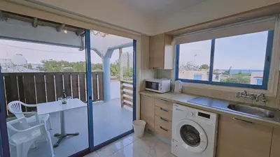 a kitchen with a washing machine and a balcony at STAY Chrisoula Beach Garden in Voroklini