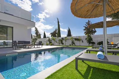 a swimming pool with chairs and an umbrella next to a house at Villa Vitalia - 3 En-suite Beds with Private Pool in Paralimni