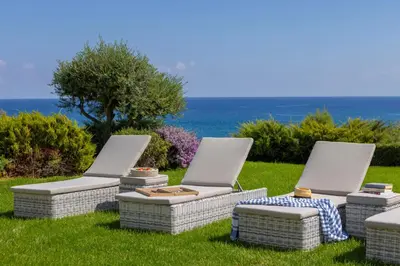 a group of three chairs sitting in the grass at Protaras Sirina Seafront Paradise in Protaras