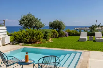 a swimming pool with a table and chairs and the ocean at Protaras Sirina Seafront Paradise in Protaras