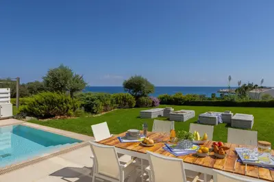 a table with fruit on it next to a swimming pool at Protaras Sirina Seafront Paradise in Protaras