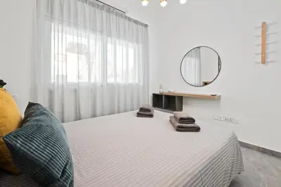 a white bedroom with a bed with towels on it at FatCow Beach Apartment in Larnaka