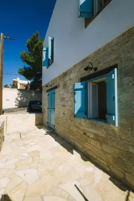a stone building with blue windows and a stone sidewalk at Dipaton House in Vasa 1 in Limassol