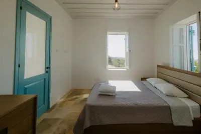 a bedroom with a bed with a blue door and a window at Dipaton House in Vasa 2 in Vasa Kilaniou