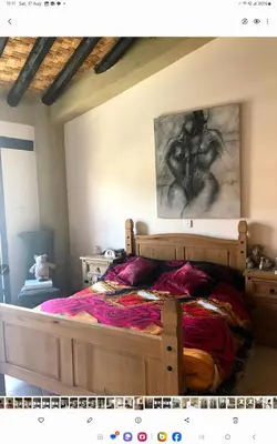 a bedroom with a wooden bed with a painting on the wall at Clover Cottage in Limassol