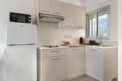a kitchen with white cabinets and a refrigerator at Phaedrus Living Larnaca Harbour Heights in Larnaka