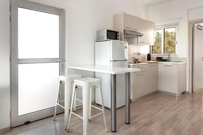 a kitchen with a table and stools and a refrigerator at Phaedrus Living Larnaca Harbour Heights in Larnaka