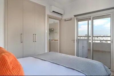 a white bedroom with a bed and a balcony at Phaedrus Living Larnaca Harbour Heights in Larnaka