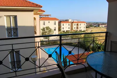a balcony with a table and a view of a pool at Mazotos Panoramic Village in Mazotos