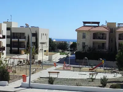a playground with benches and slides in front of a building at Mazotos Panoramic Village in Mazotos