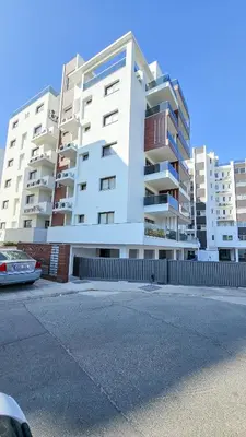 a large white apartment building with a parking lot at Modern Wellness Escape Apartment with Optional Health Transformation Retreat in Larnaka