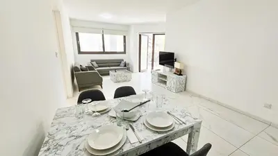 a white living room with a table and chairs at Modern Wellness Escape Apartment with Optional Health Transformation Retreat in Larnaka