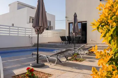 a patio with two umbrellas next to a pool at Marios Villa in Larnaka