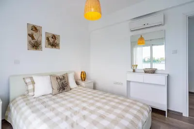 a white bedroom with a bed and a window at Corali Villa in Pernera Protaras in Paralimni