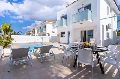 a patio with a table and chairs next to a pool at Corali Villa in Pernera Protaras in Paralimni