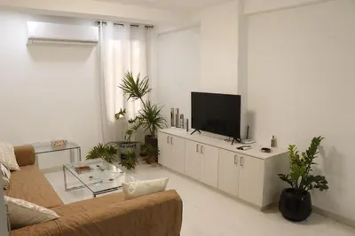 a living room with a couch and a flat screen tv at Spacious Apartment, NEAR PINIKOUDES BEACH in Larnaka