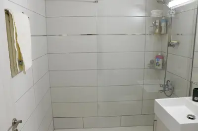a white bathroom with a shower and a sink at Spacious Apartment, NEAR PINIKOUDES BEACH in Larnaka