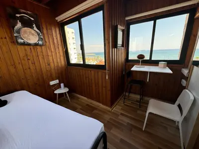 a bedroom with a bed and a desk and windows at It can't be more central Larnaca in Larnaka