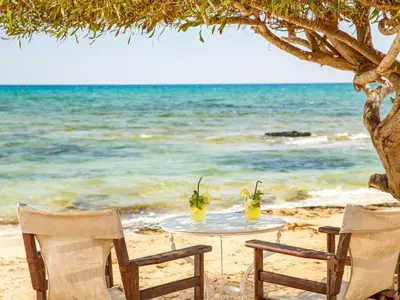 a table with two drinks on the beach at Sanders Breeze Limassol in Limassol