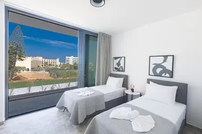 two beds in a room with a large window at Aqua Pearl Villas in Protaras
