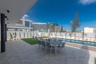 a patio with a table and chairs next to a pool at Aqua Pearl Villas in Protaras