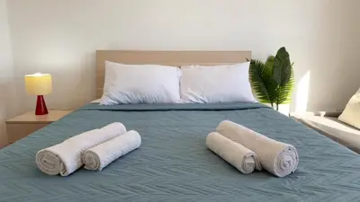 a bed with three rolled towels on top of it at Kolonaki Seaview 1BDR Finikoudes in Larnaka