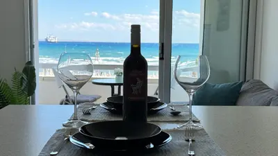 a bottle of wine sitting on a table with two wine glasses at Kolonaki Seaview 1BDR Finikoudes in Larnaka