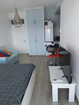 a bedroom with a bed and a desk and a kitchen at Seafront City Center Studio in Limassol