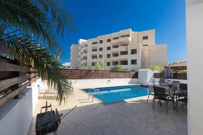 a swimming pool with chairs and a table next to a building at Protaras Blue River Villa BR26 in Protaras