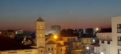 a building with a clock tower in a city at night at D Pitsillos Homes in Larnaka