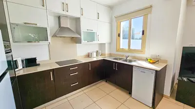 a kitchen with brown cabinets and a sink and a window at Palmvibes Villa With Private Pool in Paralimni