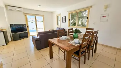 a dining room with a table and a couch at Palmvibes Villa With Private Pool in Paralimni