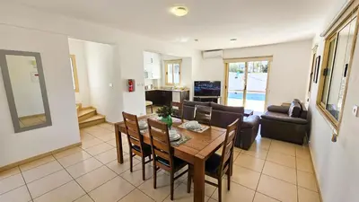 a dining room and living room with a table and chairs at Palmvibes Villa With Private Pool in Paralimni