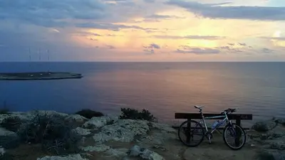a bike parked on a bench next to the water at Odessa Beach Hotel in Protaras